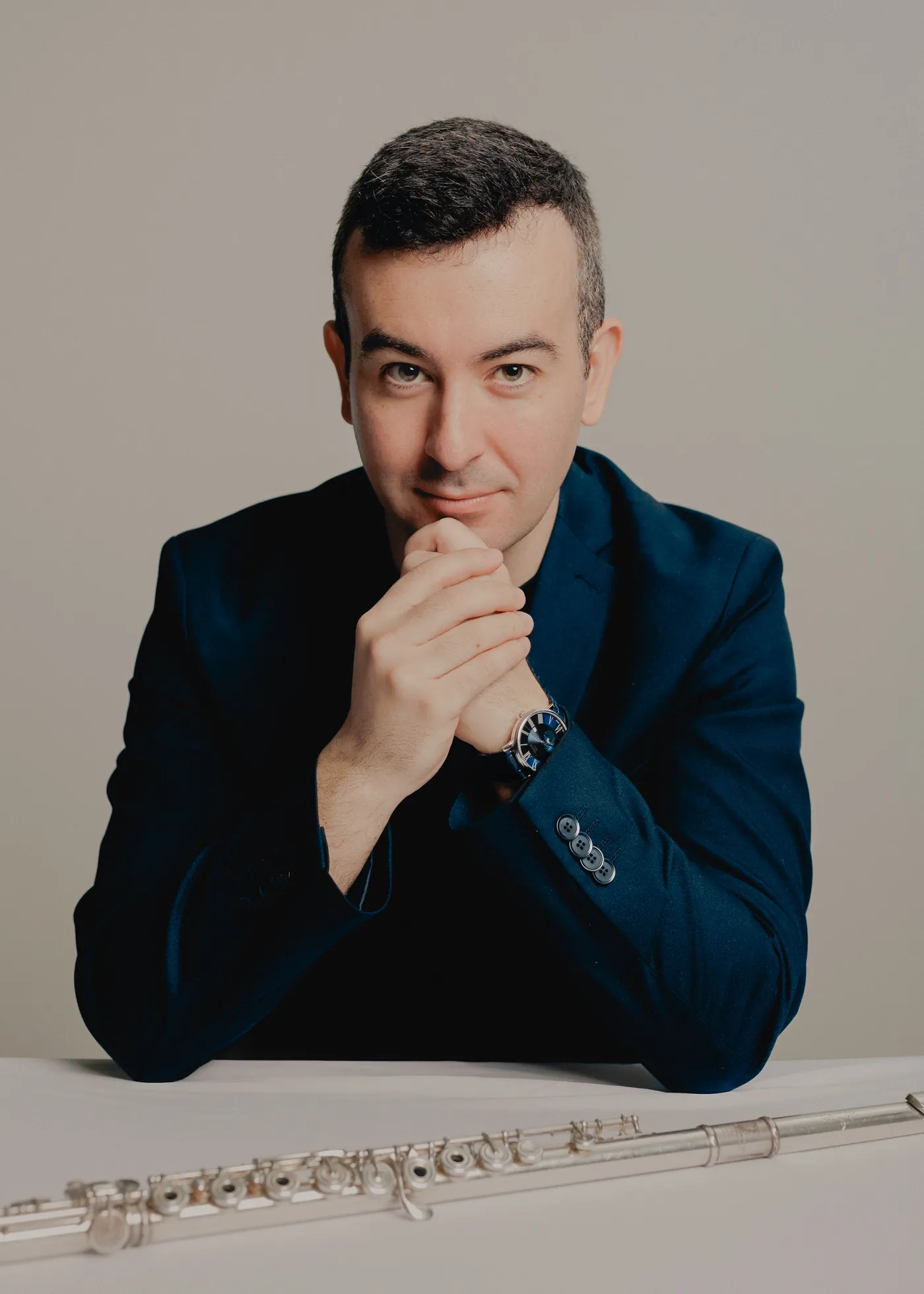 Alberto Acuña seated at a table, hands clasped, flute in front of him