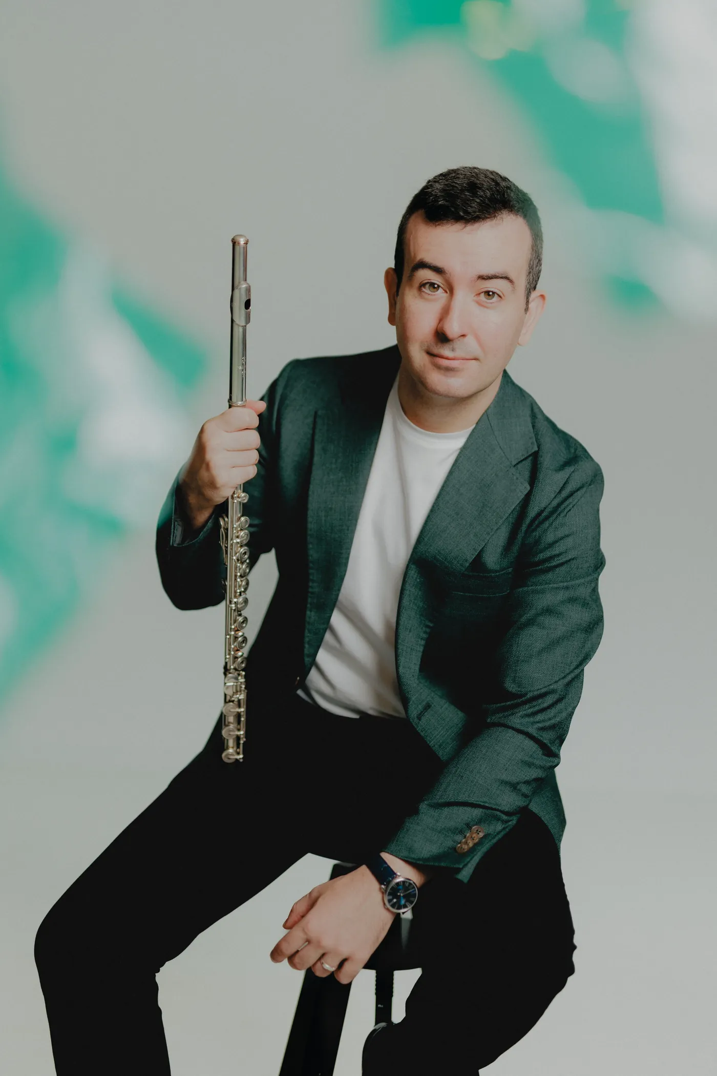 Alberto Acuña seated with his flute in a green-lit studio