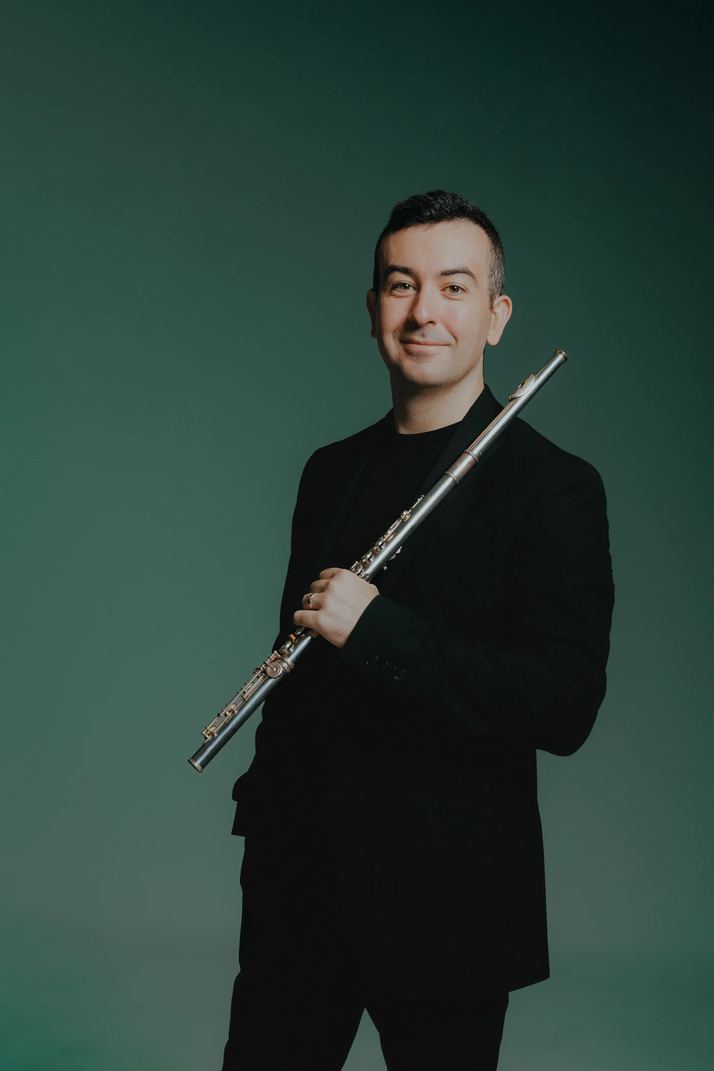 Alberto Acuña standing with his flute against a deep green background