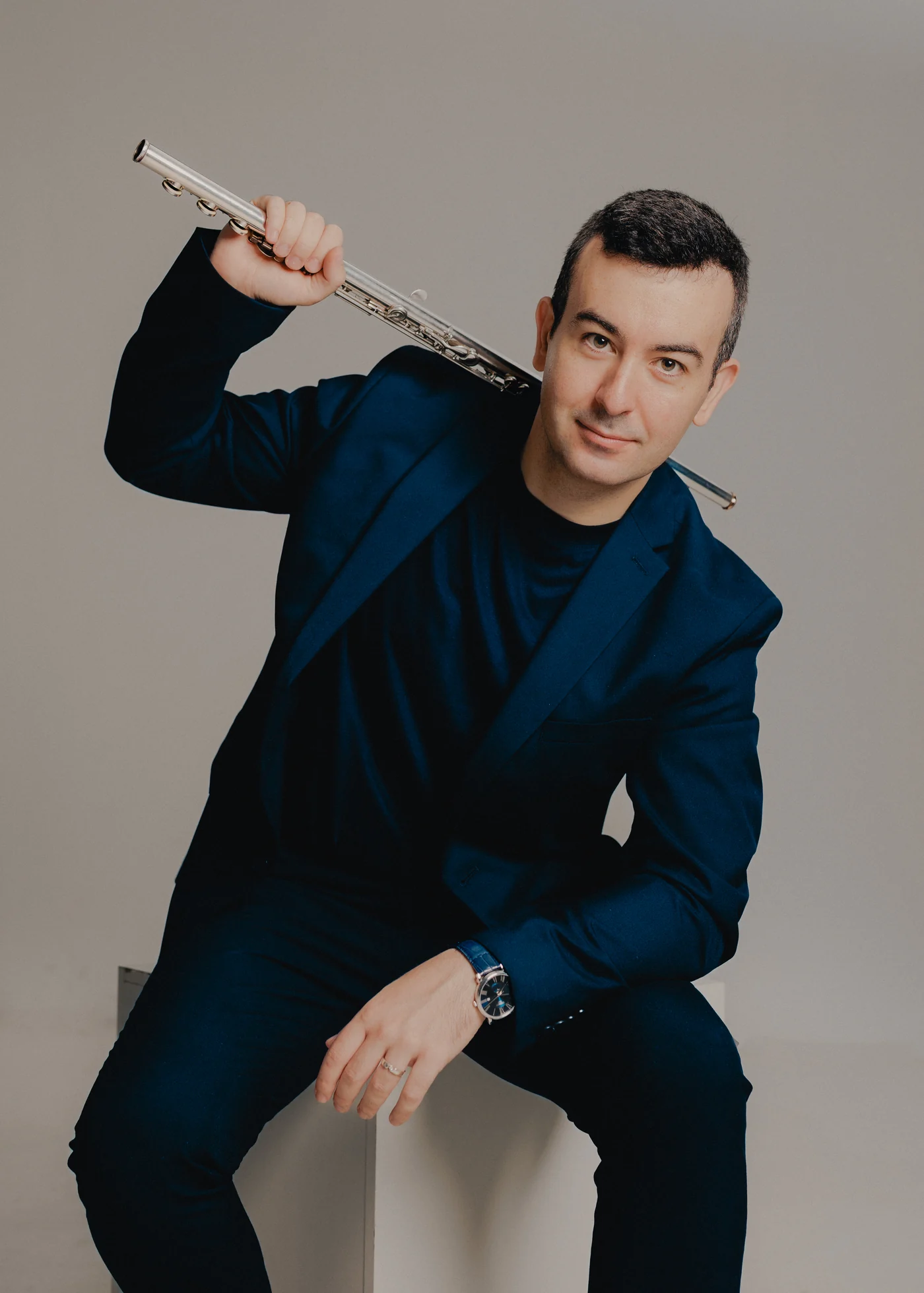 Portrait of Alberto Acuña in a navy suit with his flute across his shoulder